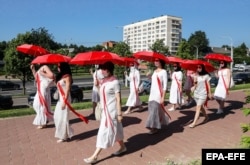 Белорусские женщины в одежде и с зонтиками в цветах белорусского национального протестного флага во время акции против режима Лукашенко. Минск, 21 июня 2021 года